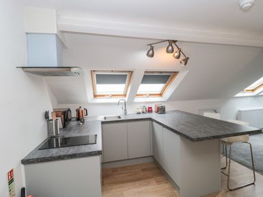 A kitchen with a gray countertop stove kettle toaster and two windows at Bay Tree House in Seaton Devon