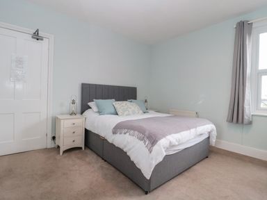 A bedroom with a double bed bedside tables and a window with curtains at Bay Tree House in Seaton Devon