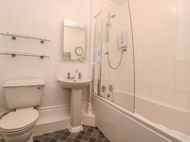 A bathroom with a toilet sink mirror bathtub and shower at Bay Tree House in Seaton Devon
