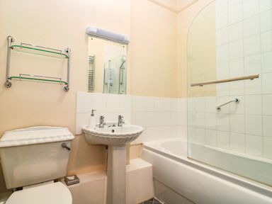A bathroom with a toilet sink mirror and bathtub with glass screen at Bay Tree House in Seaton Devon
