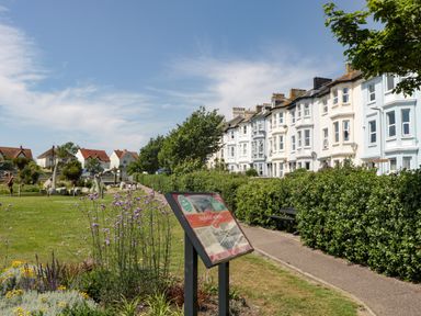 A park with flowers and an information board beside a row of residential buildings at Bay Tree House in Seaton Devon