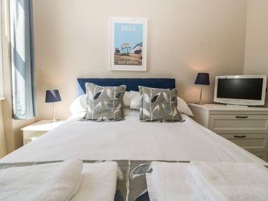 A bedroom with a bed two pillows two bedside tables two lamps a television and a framed picture at Bay Tree House in Seaton Devon