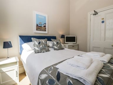 A bedroom with a double bed two bedside tables lamps and a television at Bay Tree House in Seaton Devon