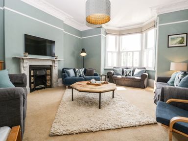 A living room with sofas around a wooden coffee table on a rug at Bay Tree House in Seaton Devon