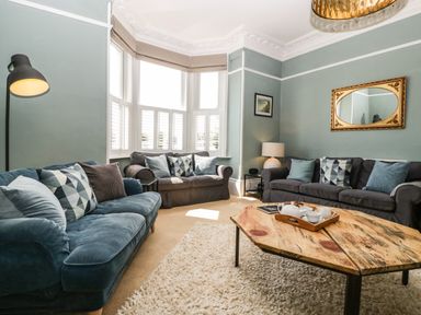 A living room with three sofas cushions a wooden coffee table a floor lamp and a table lamp by Bay Tree House in Seaton Devon