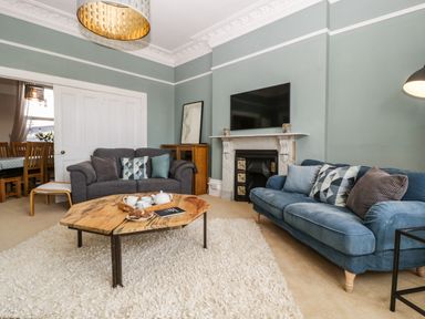 A living room with two sofas a wooden coffee table and a fireplace at Bay Tree House in Seaton Devon