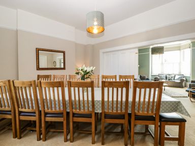 A dining room with a long table and wooden chairs with a vase of flowers on the table at Bay Tree House in Seaton Devon