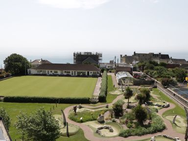 An outdoor area with a bowling green and mini golf course near buildings and the sea at Bay Tree House in Seaton Devon