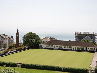 A bowling green with a clubhouse and a clock tower near the sea at Bay Tree House in Seaton Devon