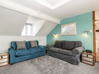 A sitting room with two sofas a mirror on a teal wall and trunks used as side tables at Bay Tree House in Seaton Devon