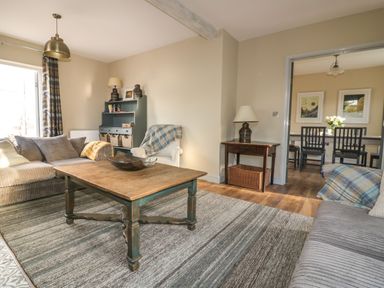 A living room with sofas table and cabinet open to dining area at Crantock Lodge in Crantock