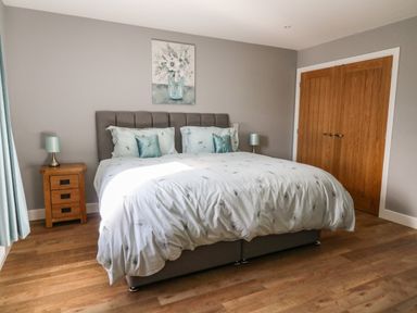 A bedroom with a double bed bedside tables with lamps a wooden floor and a double wooden door at Talarddu Cottage in Builth Wells