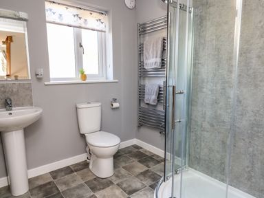 A bathroom with a shower enclosure toilet sink and towel rack at Talarddu Cottage in Builth Wells