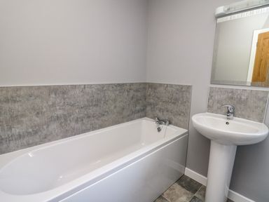 A bathroom with a bathtub sink and mirror at Talarddu Cottage in Builth Wells
