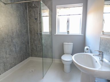 A bathroom with a walk-in shower, toilet, sink, and window at Talarddu Cottage in Builth Wells