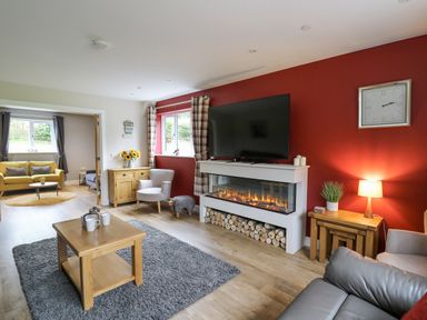 A living room with a fireplace television and wooden furniture at Talarddu Cottage in Builth Wells