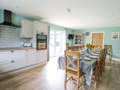 A kitchen and dining area with wooden chairs and a table with a polka dot tablecloth at Talarddu Cottage in Builth Wells