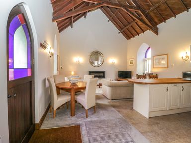 An open living space with a dining table and chairs a sofa a television and kitchen island at Frogwell Chapel in Frogwell near Callington