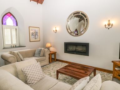 A living room with sofas wooden coffee table and wall-mounted fireplace at Frogwell Chapel in Frogwell near Callington