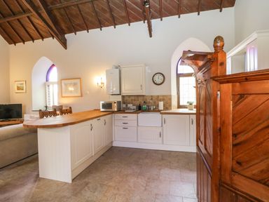 A kitchen with white cabinets a wooden countertop and a wooden staircase at Frogwell Chapel in Frogwell near Callington