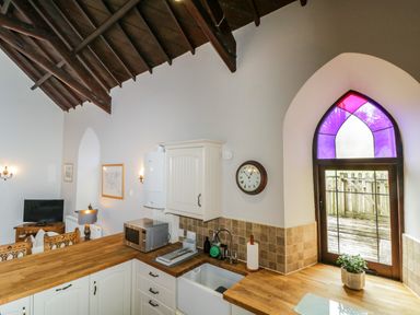A kitchen with wooden countertops a microwave a sink and a stained glass window at Frogwell Chapel in Frogwell near Callington