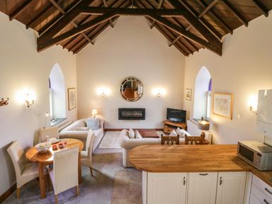 A living room with a dining table chairs sofas a fireplace and a kitchen counter at Frogwell Chapel in Frogwell near Callington