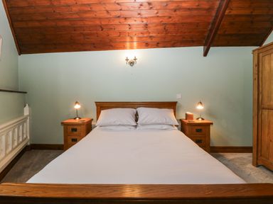 A bedroom with a wooden bed and two bedside tables with lamps at Frogwell Chapel in Frogwell near Callington