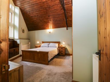 A bedroom with a wooden bed and bedside tables under a sloped wooden ceiling at Frogwell Chapel in Frogwell near Callington