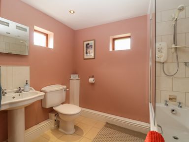 A bathroom with a toilet, sink, bathtub, shower, and two small windows at Frogwell Chapel in Frogwell near Callington
