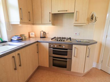 A kitchen corner with a gas stove oven kettle and wooden cabinets at Limhus Cottage in Keswick