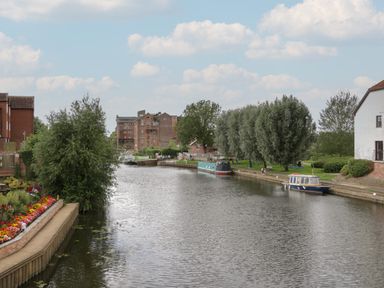 A river with boats docked along its banks and trees lining the sides at Avonmede in Tewkesbury