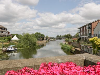 A river with boats and buildings along the bank at Avonmede in Tewkesbury