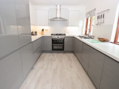 A kitchen with grey cabinets and gas stove at Fir Trees in Bowness-On-Windermere