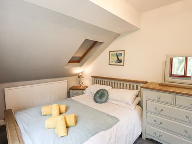 A bedroom with a bed with yellow towels on it a bedside table with a lamp a chest of drawers and a skylight window at Fir Trees in Bowness-On-Windermere