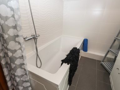 A bathroom with a bathtub shower and a gray and white cloud patterned shower curtain at Fir Trees in Bowness-On-Windermere