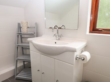 A bathroom with a white sink cabinet mirror window and a small gray shelf with a pitcher at Fir Trees in Bowness-On-Windermere