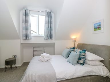 A bedroom with a bed with pillows and towels under a window with curtains at The Sanctuary in Windermere
