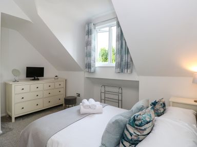 A bedroom with a bed pillows a dresser small TV and a window at The Sanctuary in Windermere