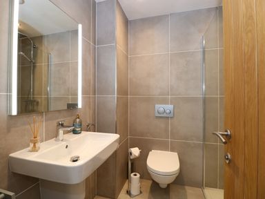 A bathroom with a sink mirror and wall mounted toilet at The Sanctuary in Windermere