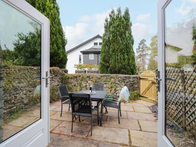 A patio with a table and four chairs outside with a wooden gate and stone wall at The Sanctuary in Windermere