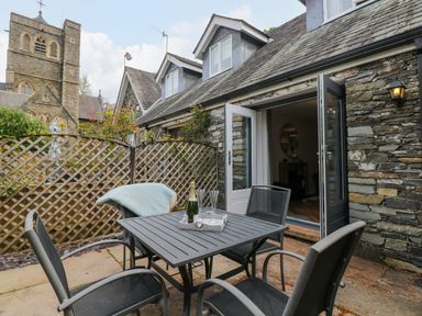 An outdoor patio with a table and four chairs next to a stone house at The Sanctuary in Windermere