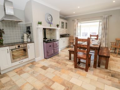 A kitchen with a dining table set with dishes and a purple stove at Deanrise in Shilbottle near Alnwick