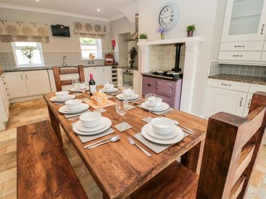A kitchen with a wooden dining table set for six and a purple stove at Deanrise in Shilbottle near Alnwick