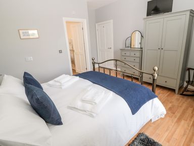 A bedroom with a bed a wardrobe a dresser with mirror and a rocking chair at Deanrise in Shilbottle near Alnwick