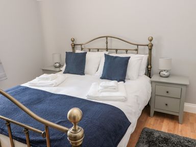 A bedroom with a metal bed frame blue cushions and blankets bedside tables with lamps at Deanrise in Shilbottle near Alnwick