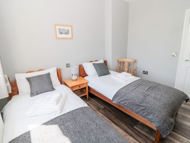 A bedroom with two single beds a side table a lamp a wooden chair and a framed picture on the wall at Deanrise in Shilbottle near Alnwick