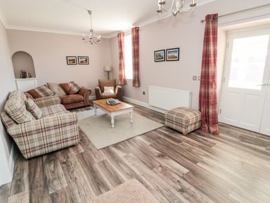 A living room with sofas armchair coffee table ottoman and framed pictures at Deanrise in Shilbottle near Alnwick