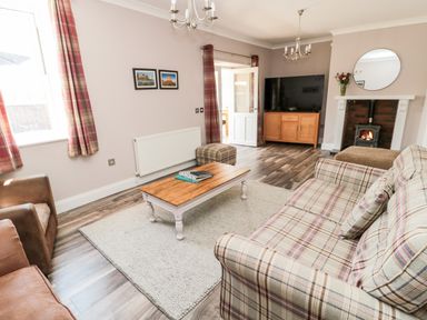 A living room with plaid sofa brown armchair coffee table and fireplace at Deanrise in Shilbottle near Alnwick