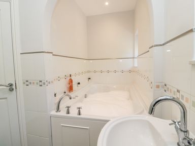 A bathroom with a bathtub filled with foam and a sink with a faucet at Deanrise in Shilbottle near Alnwick