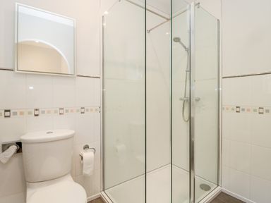 A bathroom with a toilet a mirror and a glass shower enclosure at Deanrise in Shilbottle near Alnwick